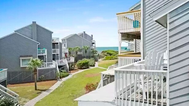 Uma área residencial à beira-mar, com vários edifícios de dois andares, um caminho visível e vista clara para o oceano.