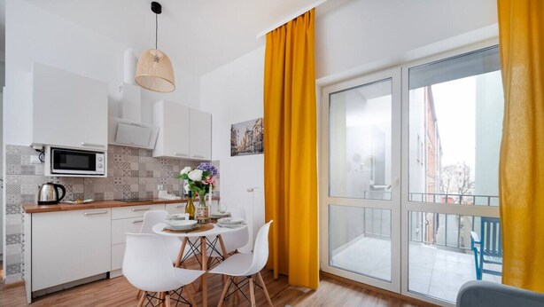 Una cocina moderna con armarios blancos, un microondas y un comedor con mesa y sillas.