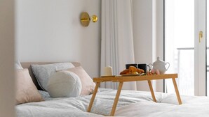 A neatly made bed with a wooden side table, pillows, and a tray with breakfast items. - Warsaw Żoliborz Apartment- Parking & Two Balconies - by Rentujemy (Warszawa)