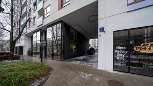 A modern building with large glass windows and a sign for 'Miesz Dwór Sery Wino'. - Warsaw Żoliborz Apartment- Parking & Two Balconies - by Rentujemy (Warszawa)