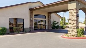 A modern building with a covered entrance, stone pillars, and a landscaped area with plants. - Hotel Rising (Phoenix)