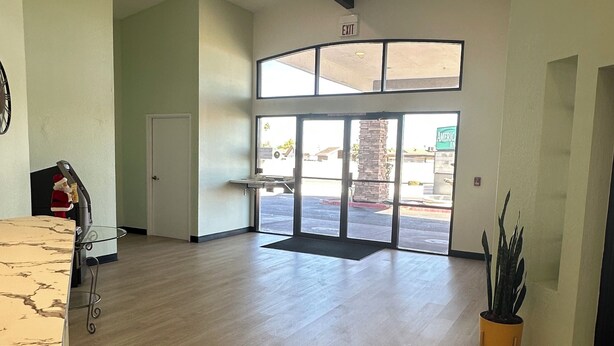 A spacious lobby with a wooden floor, a reception desk, and a large glass door leading outside. - Hotel Rising (Phoenix)