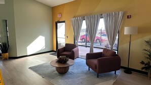 A spacious lobby with two sofas, a coffee table, and a large window with curtains. - Hotel Rising (Phoenix)
