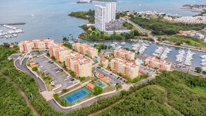 A residential area with apartment buildings, a marina with boats, and a tennis court. - Ocean View in a central apartment w/ pool and gym (Fajardo)