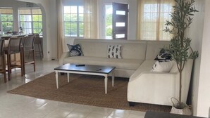 Uma sala de estar ampla, com sofá, mesa de centro e área de jantar.