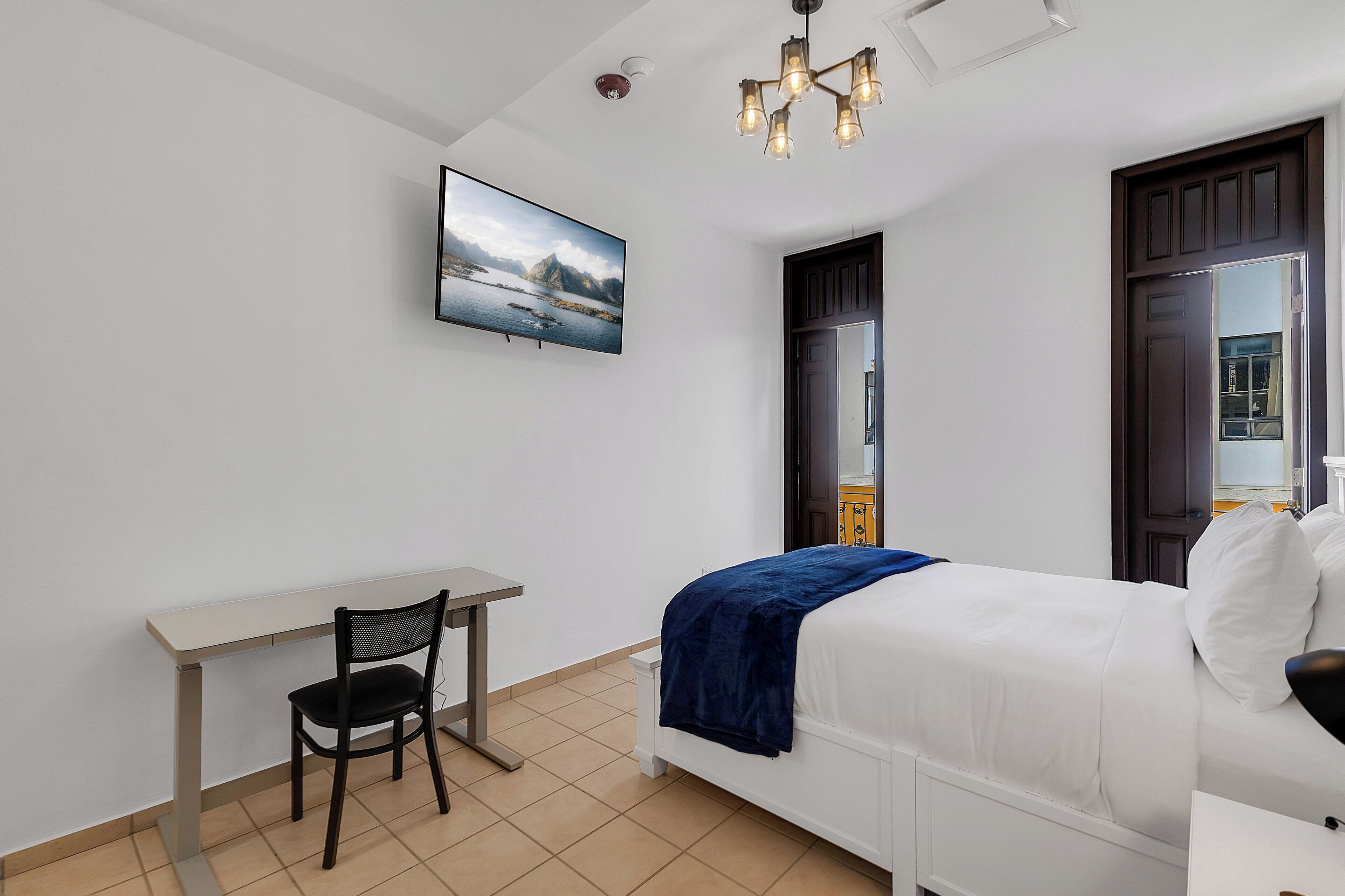 A bedroom with a bed, a desk, and a chair.