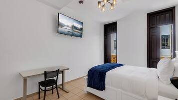 A bedroom with a bed, a desk, and a chair.