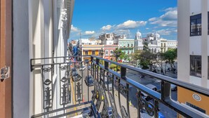Ein Balkon mit Blick auf eine Straße und Gebäude, darunter eine Kirche mit einem Glockenturm.
