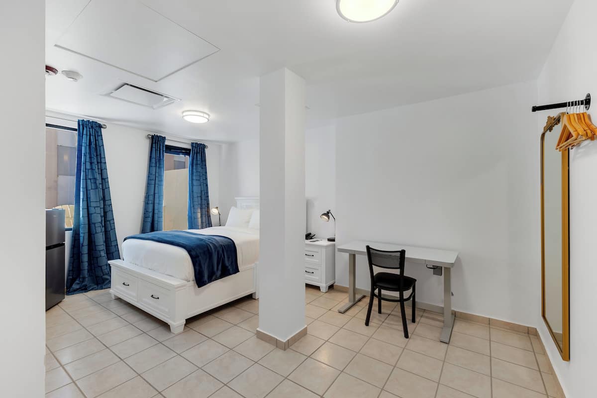 Une chambre d’hôtel moderne équipée d’un lit, d’un bureau, d’une chaise et d’une armoire.