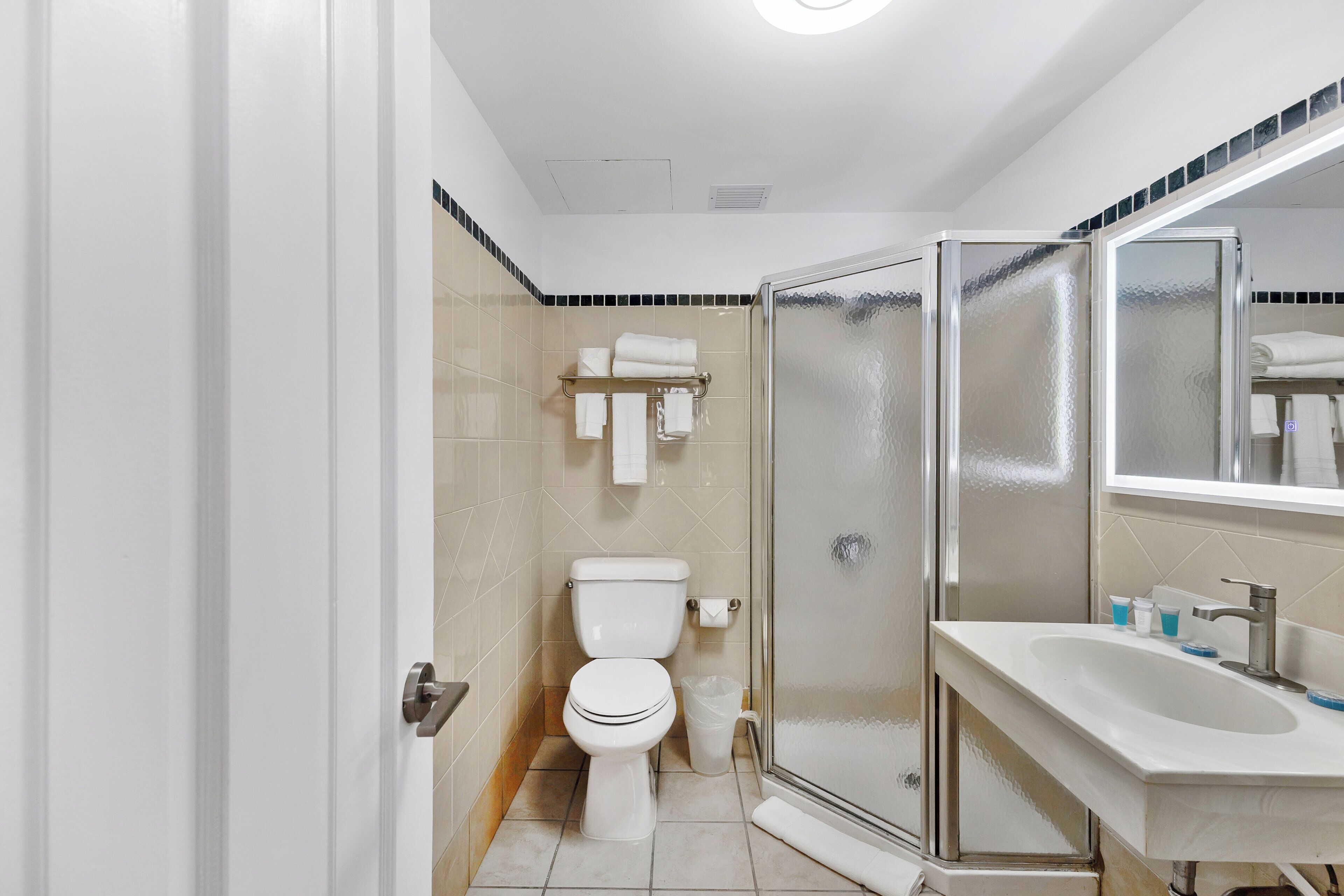 Une salle de bain moderne comprenant des toilettes, une douche à parois de verre et un lavabo avec un miroir.