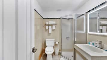 Une salle de bain moderne comprenant des toilettes, une douche à parois de verre et un lavabo avec un miroir.