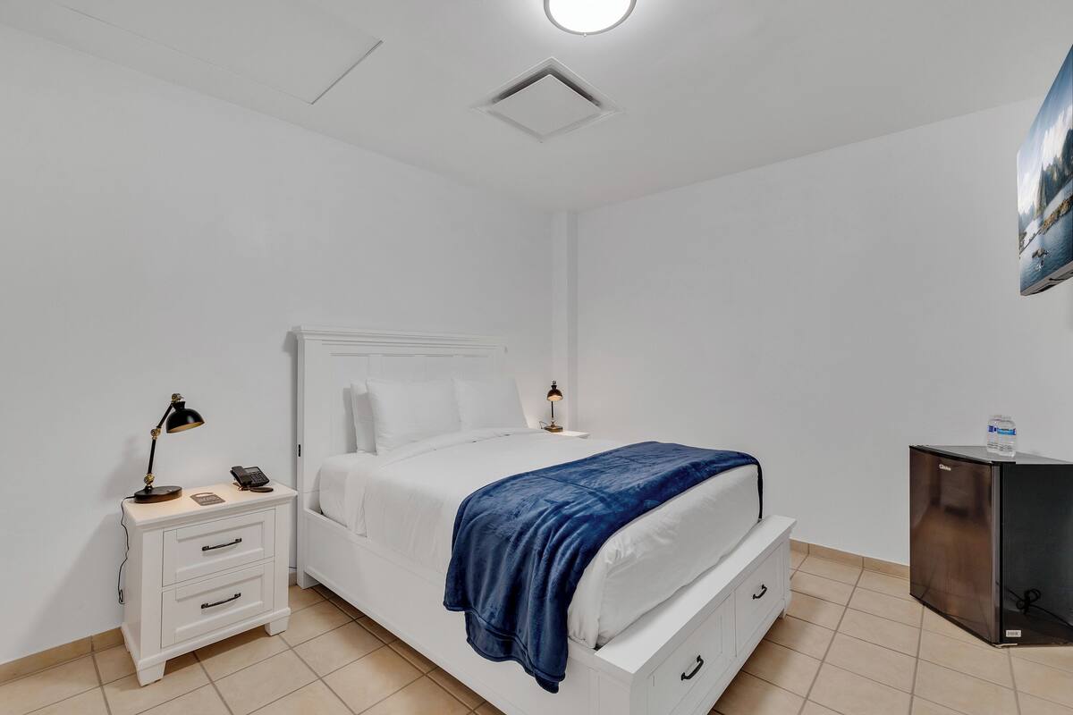 Une chambre à coucher comprenant un lit, une table de chevet avec une lampe, une commode et un petit meuble de rangement.