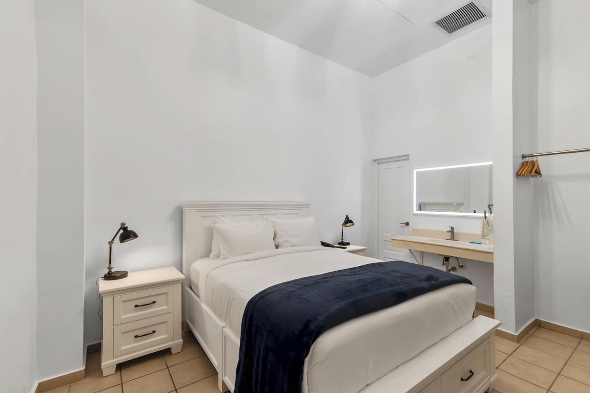 Une chambre à coucher comprenant un lit, des tables de chevet, un miroir et une armoire.