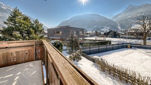 A wooden deck overlooking a snowy landscape with mountains in the background.