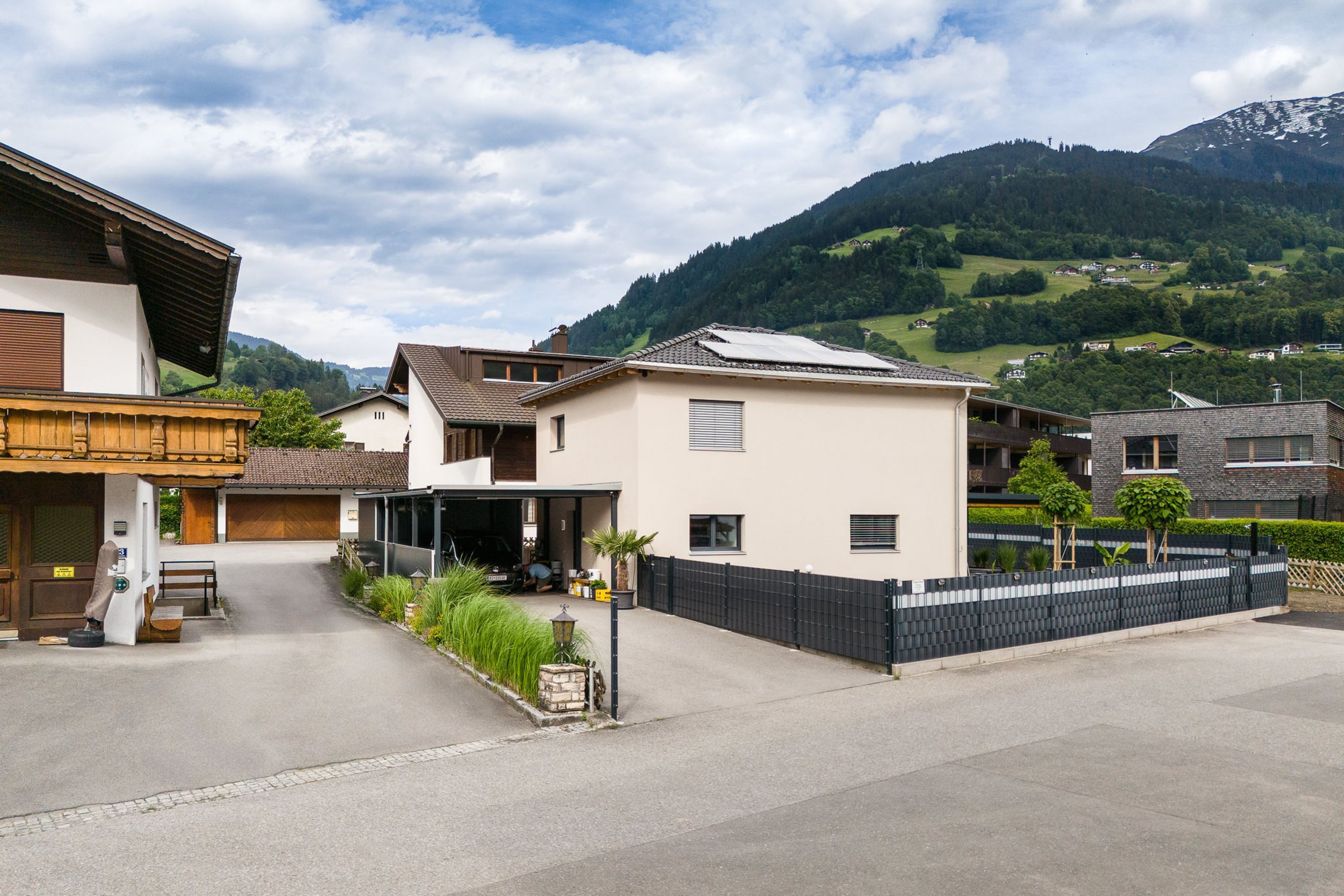 A residential street with houses, a garage, and a mountain backdrop.