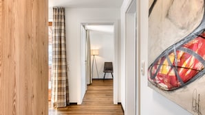 A hallway with wooden flooring, a plaid curtain, a lamp, and a chair.