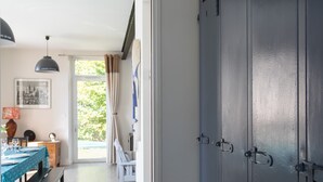 Una habitación con una mesa de comedor preparada para dos, un banco, una lámpara colgante y una puerta con manija.
