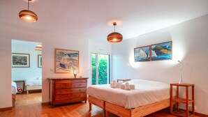Un dormitorio con cama de madera, cómoda y dos lámparas colgantes.