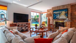 Una sala de estar moderna con un televisor de pantalla plana grande, asientos cómodos, una chimenea y vistas al exterior.
