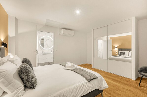Un dormitorio moderno con una cama grande, una tocador con espejo y un armario con espejo.
