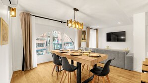 Een moderne eetruimte met een houten tafel, zwarte stoelen en een kroonluchter.