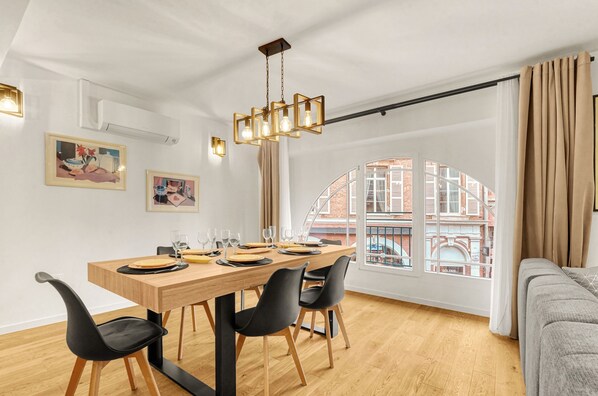A dining area with a wooden table, black chairs, and a hanging light fixture.