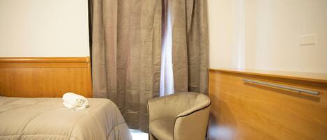 Een hotelkamer met een bed, een stoel en een houten kast.