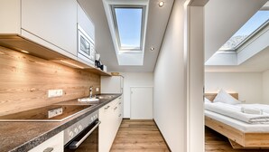 A modern kitchen with a skylight, wooden flooring, and a compact layout. - Alpenblick Appartements - 3-zimmer Dachgeschoss (Schruns)