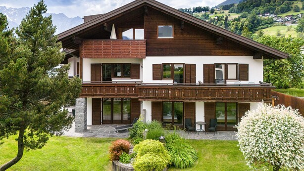 A two-story chalet with a balcony, stone foundation, and a view of the surrounding mountains. - Alpenblick Appartements - 3-zimmer Dachgeschoss (Schruns)