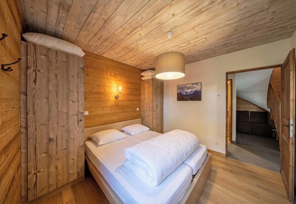 Ein Zimmer mit Holzwänden, einem Bett, einer Wandleuchte und einem Bild.