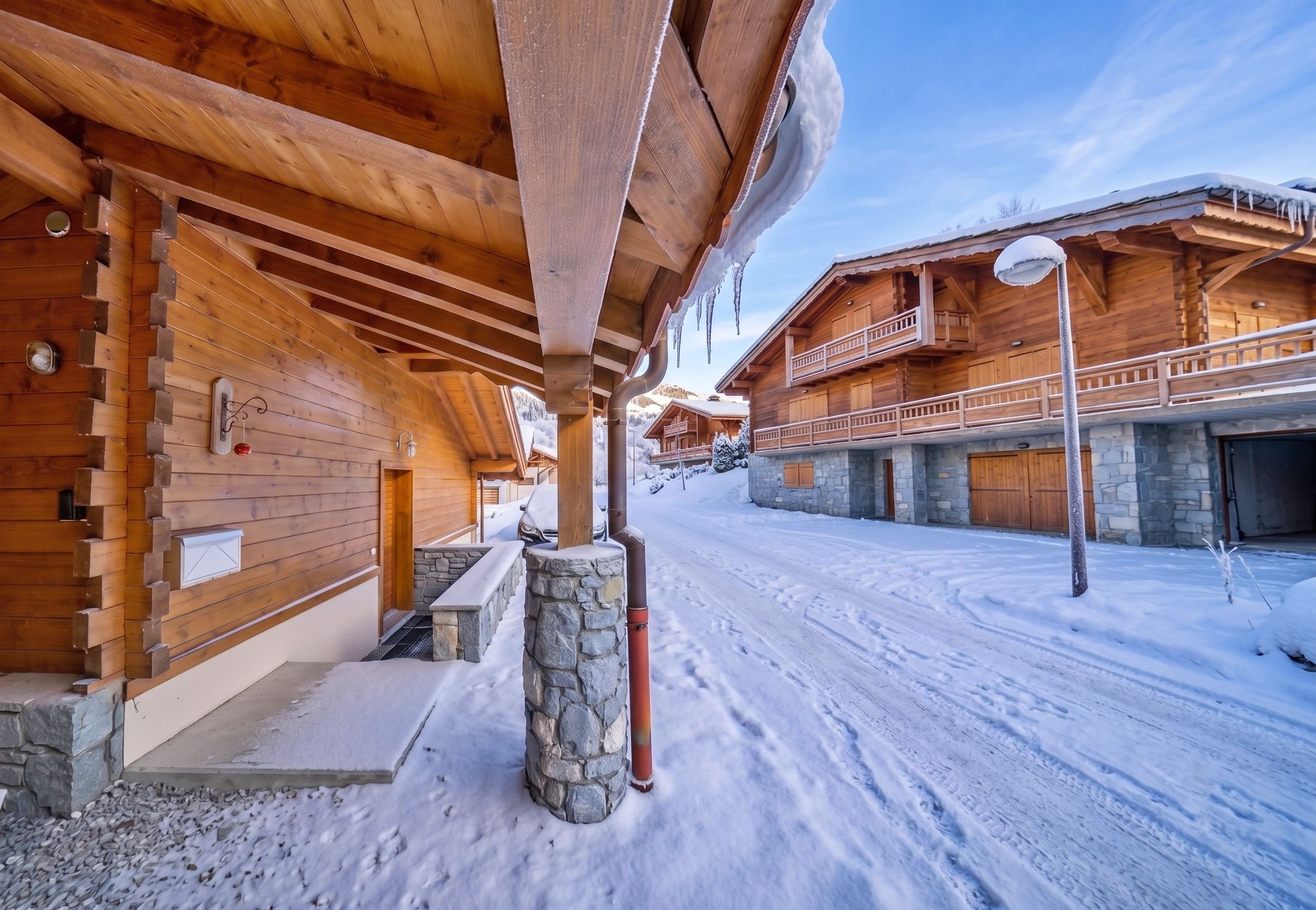 Une cabane en bois avec des fondations en pierre, un balcon et un sol recouvert de neige.