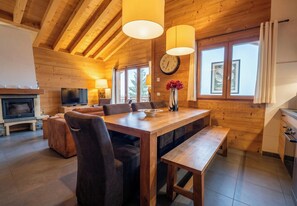 Ein Holzinnenraum mit Essbereich, Kamin, Fernseher und einer Wanduhr.