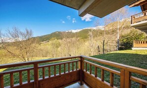 A wooden balcony with a view of a mountainous landscape.