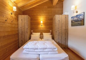 Une pièce aux murs lambrés, avec un lit, deux lampes fixées au mur et un tableau encadré accroché au mur.