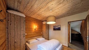 Una habitación de madera con una cama, una lámpara en la pared y una puerta que da a una escalera.