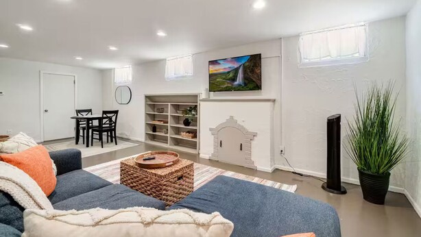 Ein modernes Wohnzimmer mit Ecksofa, Essbereich, Bücherregal und Kamin.