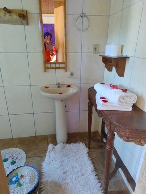 A bathroom with a white sink, a wooden vanity, a mirror, and a towel rack.