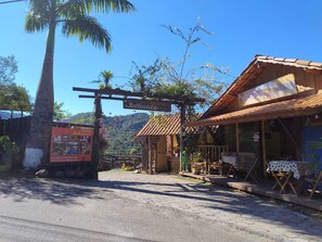 A rustic wooden building with a tiled roof, a signboard above the entrance, and a paved pathway leading to it.