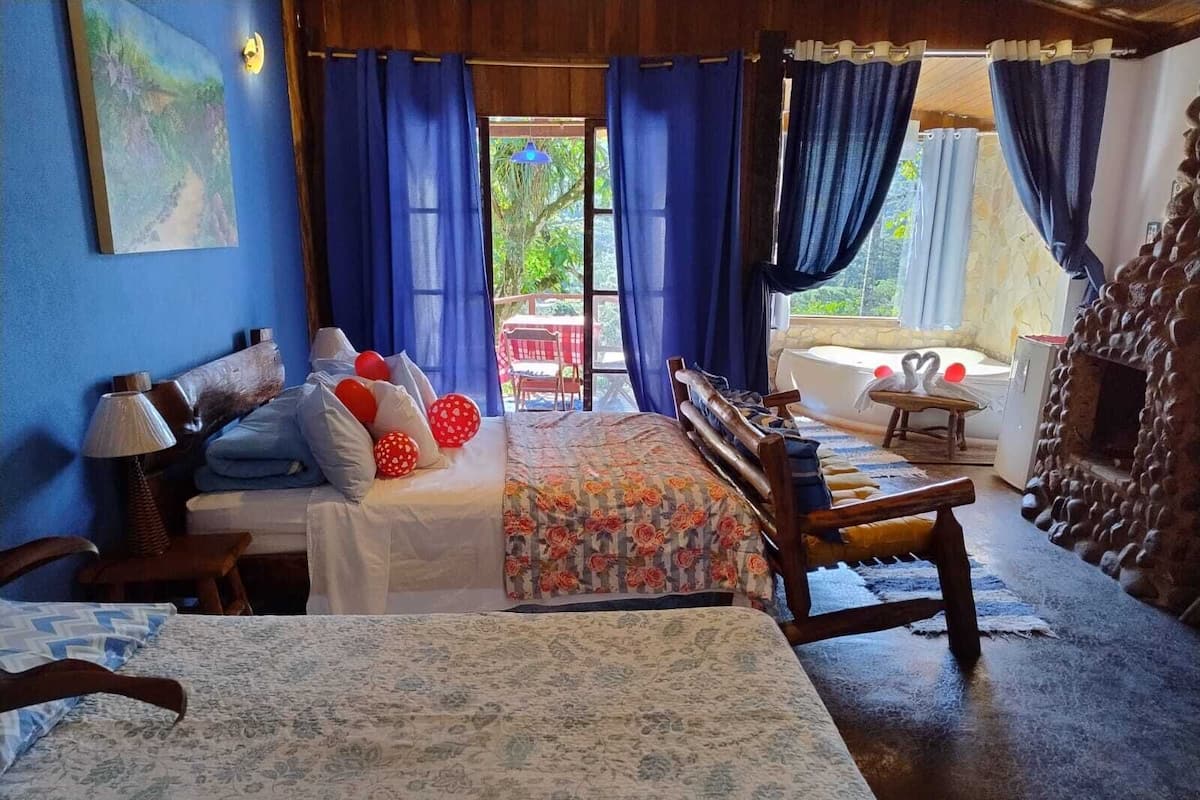 A cozy room with a bed, a wooden bench, a table, and a bathtub.