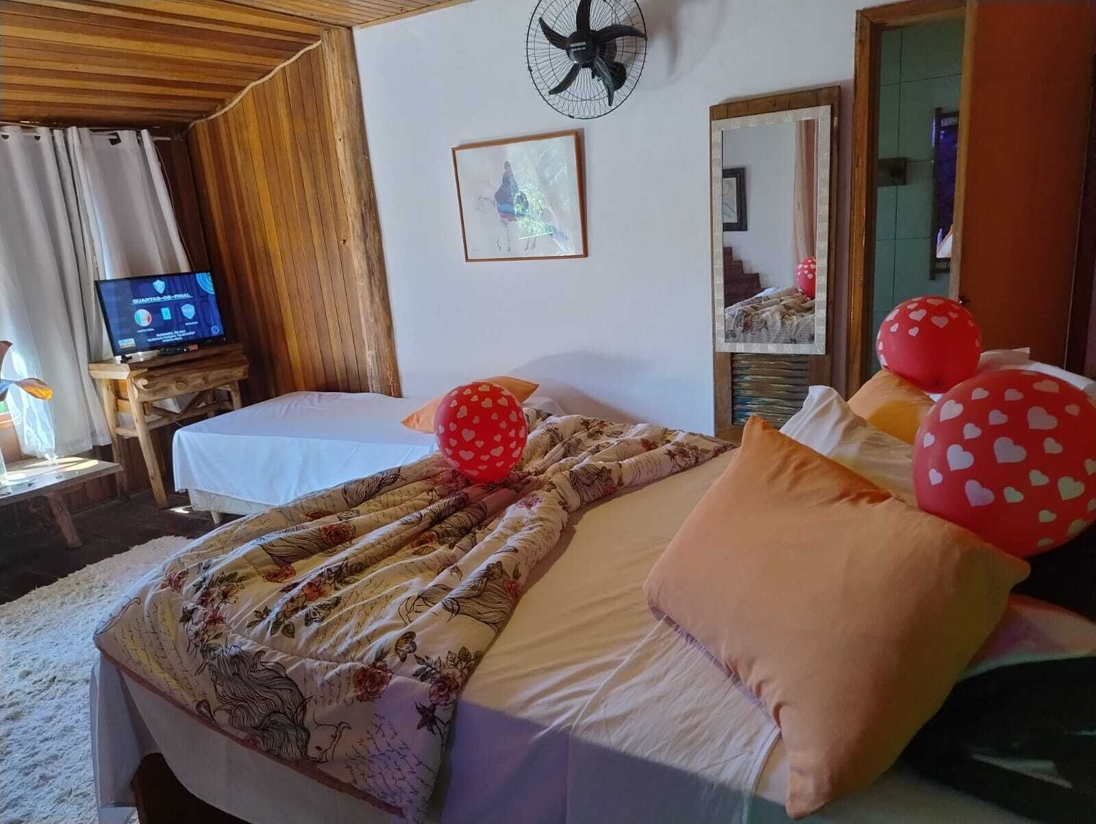 A hotel room with a bed, a television, a clock, and a mirror.
