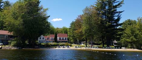 A lakeside property with multiple buildings, outdoor seating, and a dock.