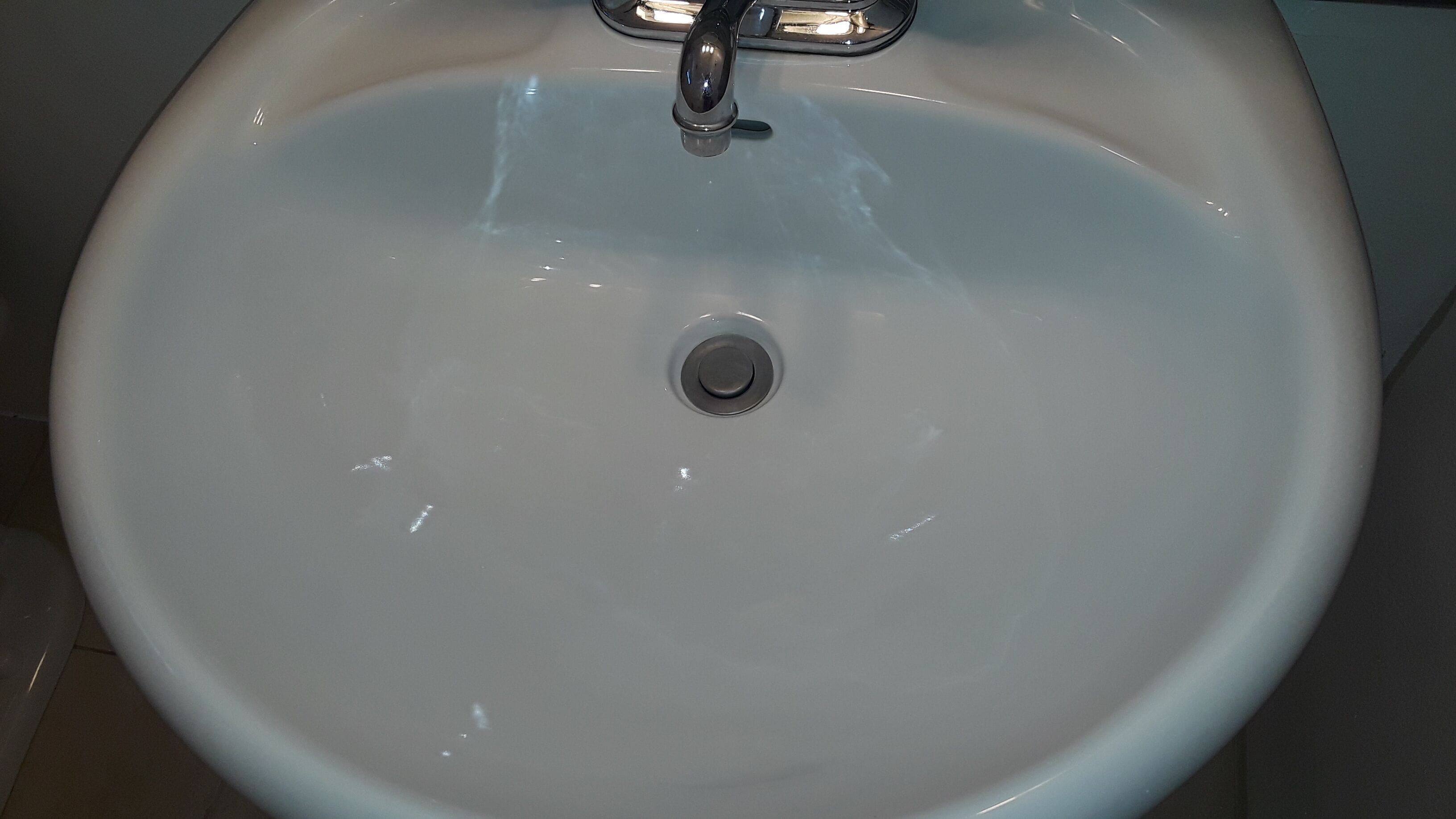 Ein weißes Keramikbecken mit einem Wasserhahn und Abfluss.