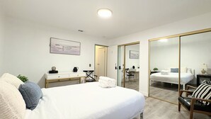 Hotellihuone, jossa on sänky, työpöytä, tuoli, peili ja vaatekaappi.