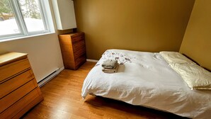 Un dormitorio con una cama, cómoda de madera y una ventana.