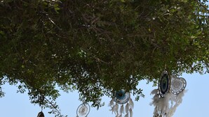 Un espace de détente aménagé sur la plage, avec des chaises longues et des attrape-rêves suspendus.