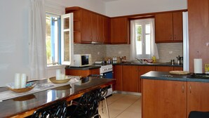A kitchen with wooden cabinets, a stove, a microwave, and a dining area with chairs.