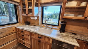 A wooden cabin kitchen with a sink, cabinets, and a coffee maker. -  Play House Private Ozone Hot Tub, w/ BEAUTIFUL views. Quaint, Cozy, & Peaceful. (Sandpoint)