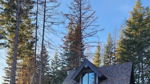 A cabin with a stone exterior, large windows, and a fire pit in the yard. -  Play House Private Ozone Hot Tub, w/ BEAUTIFUL views. Quaint, Cozy, & Peaceful. (Sandpoint)