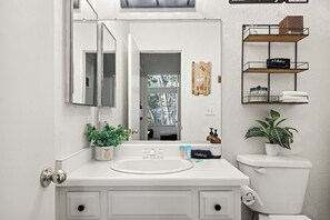 A bathroom with a white sink, a mirror, a toilet, and a shelf with toiletries. - Summit Slope Side + Steps 2 Slopes! (Big Bear Lake)