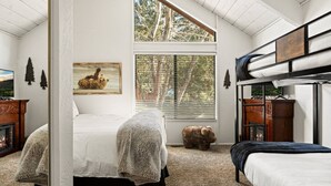 A bedroom with a bunk bed, a fireplace, a large window with blinds, and a bear-themed painting. - Summit Slope Side + Steps 2 Slopes! (Big Bear Lake)